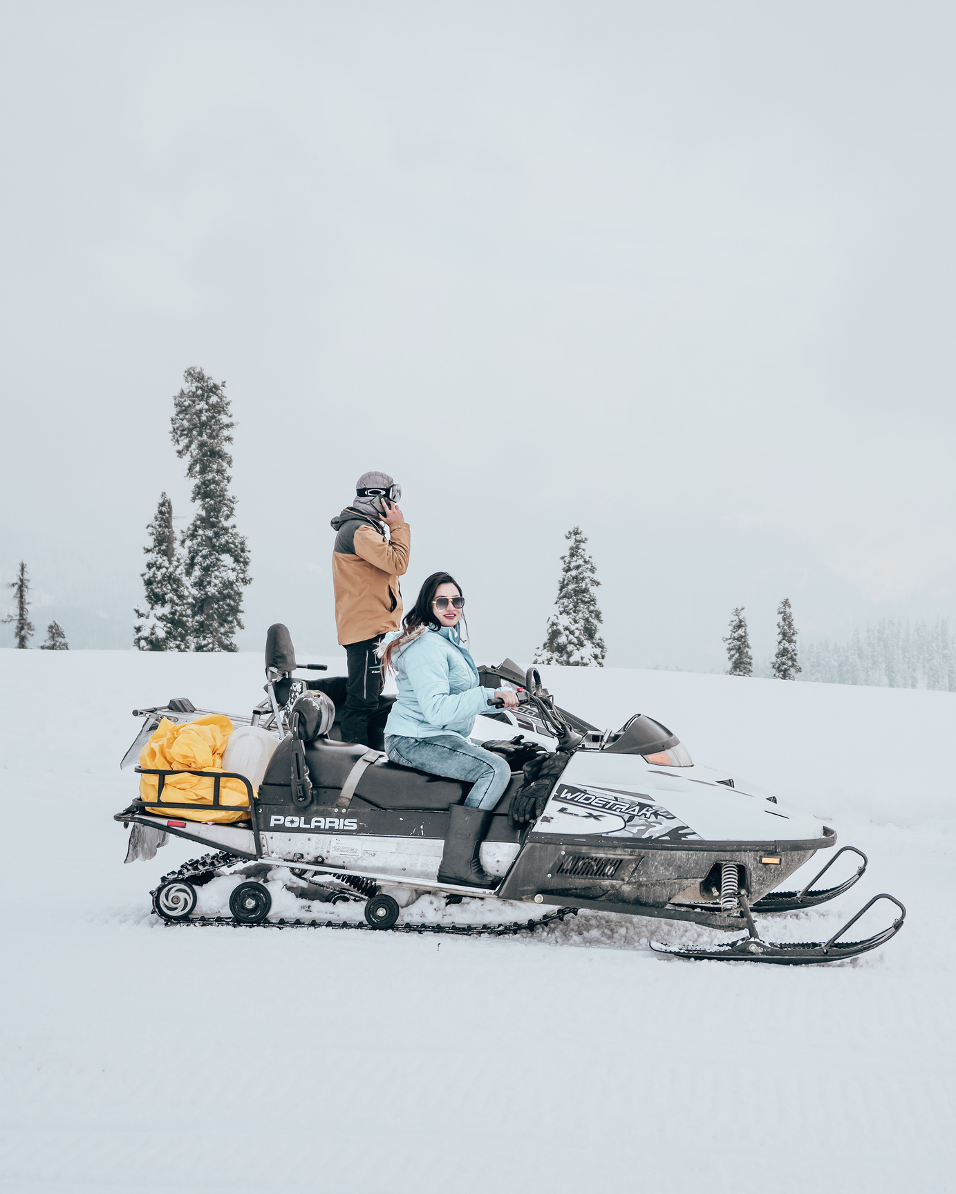 2 Women Riding on Black and Orange Snow Mobile